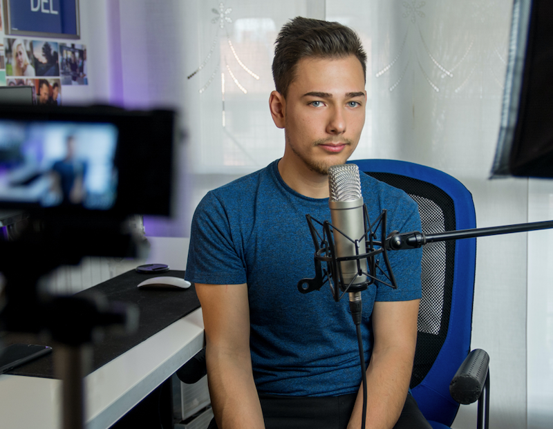 A man sitting in front of a microphone being filmed