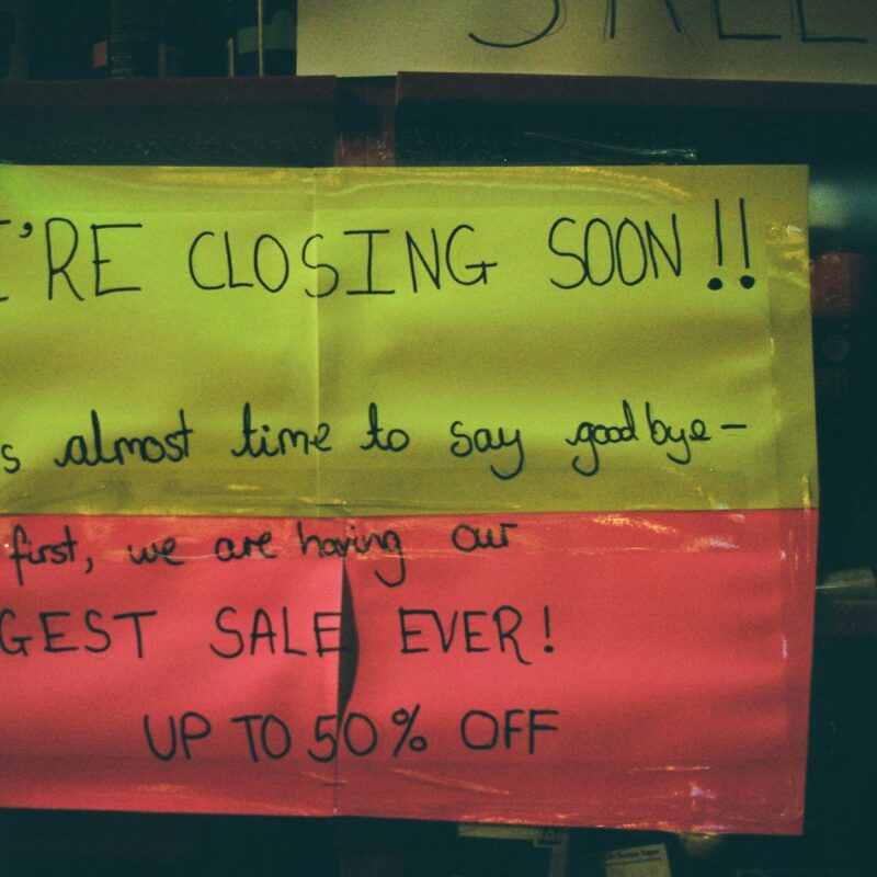 Sign on small business door that reads we're closing soon.
